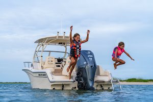 Grady-White's Adventure 218 21-foot walkaround cabin boat anchored near shore as girls jump from stern