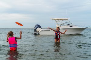 Grady-White's Adventure 218 21-foot walkaround cabin boat anchored near shore as girls play